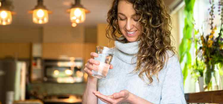 Female holding organic Lion's Mane supplement capsules and drink